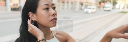 Photo for Close-up of pretty girl standing at public transport stop, analyzing the schedule of transport on the information board, chooses route, Panorama - Royalty Free Image