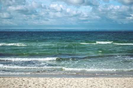 Foto de Mar turquesa con arena amarilla en la orilla contra un cielo azul con nubes - Imagen libre de derechos