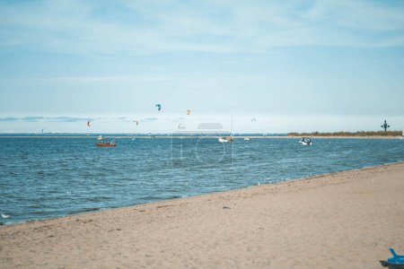 Foto de Surfistas de kitesurf flotan en tablas con un paracaídas en la bahía de mar en un día soleado - Imagen libre de derechos