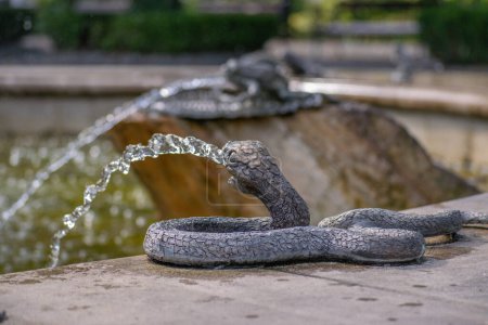 Foto de Un elemento fuente en forma de serpiente metálica que vierte un chorro de agua de su boca - Imagen libre de derechos