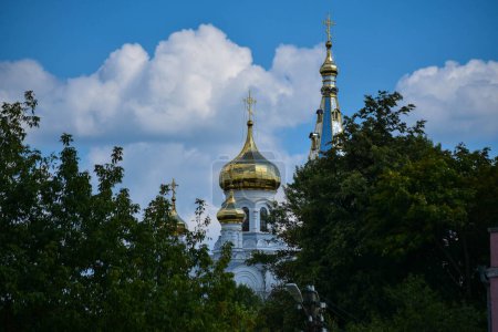 Foto de Domos ortodoxos con cruces doradas en el techo de la iglesia entre árboles verdes - Imagen libre de derechos