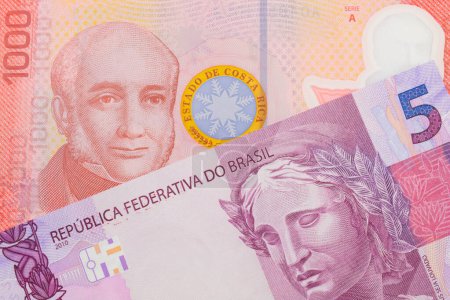 Foto de Una imagen macro de un billete de cinco reales rosa y púrpura de Brasil emparejado con un colorido billete rojo de mil colones de Costa Rica. Disparo de cerca en macro. - Imagen libre de derechos