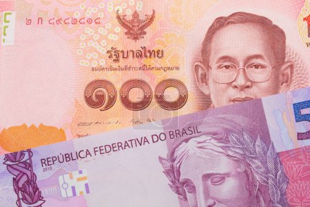 Foto de Una imagen macro de un billete de cinco reales rosa y púrpura de Brasil emparejado con un billete rojo de cien baht de Tailandia. Disparo de cerca en macro. - Imagen libre de derechos