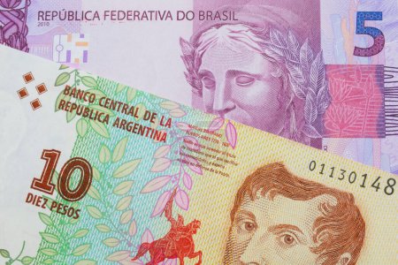 Photo for A macro image of a pink and purple five real bank note from Brazil paired up with a colorful ten peso note from Argentina.  Shot close up in macro. - Royalty Free Image