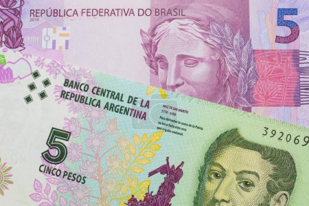 Téléchargez les photos : Une image macro d'un billet de banque rose et violet de cinq vraies du Brésil jumelé avec un billet de cinq peso coloré de l'Argentine. Plan rapproché dans macro. - en image libre de droit