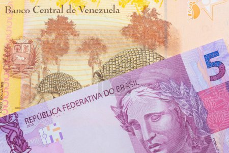 Téléchargez les photos : Une image macro d'un billet de banque rose et violet de cinq vraies du Brésil jumelé avec un coloré, jaune cinq Bolivar billet de banque du Venezuela. Plan rapproché dans macro. - en image libre de droit