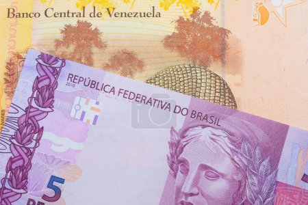 Téléchargez les photos : Une image macro d'un billet de banque rose et violet de cinq vraies du Brésil jumelé avec un coloré, jaune cinq Bolivar billet de banque du Venezuela. Plan rapproché dans macro. - en image libre de droit