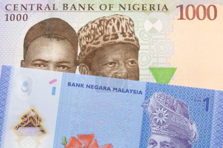 Photo for A macro image of a blue, purple and green one thousand  naira note from Nigeria paired up with a blue, plastic one ringgit bank note from Malaysia.  Shot close up in macro. - Royalty Free Image