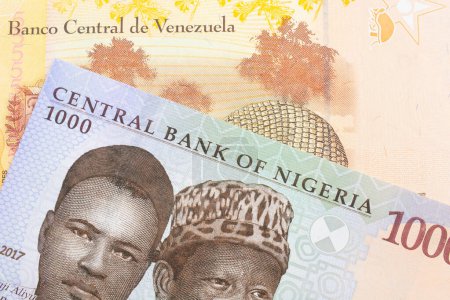 Téléchargez les photos : Une image macro d'un billet de mille nairas bleu, violet et vert du Nigeria jumelé à un billet de banque coloré et jaune de cinq Bolivar du Venezuela. Plan rapproché dans macro. - en image libre de droit