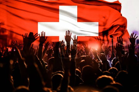 Téléchargez les photos : Supporters de football soutenant la Suisse - foule célébrant dans le stade avec les mains levées contre le drapeau suisse - en image libre de droit
