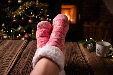 Téléchargez les photos : Femme portant des chaussettes d'hiver en laine rose devant la cheminée - en image libre de droit
