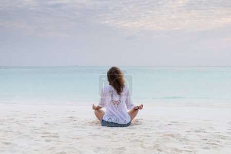 Foto de Mujer en postura de meditación junto al mar - Imagen libre de derechos