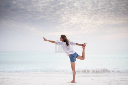 Foto de Mujer haciendo yoga por el mar colores pastel - Imagen libre de derechos