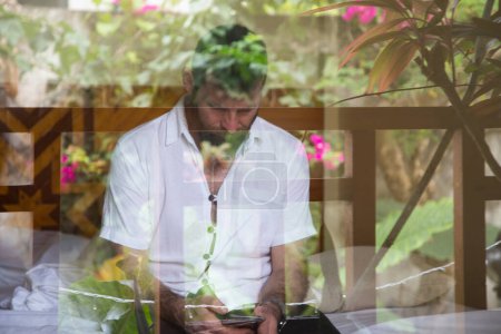 Téléchargez les photos : Bel homme regardant par la fenêtre réfléchissant les plantes tropicales santé mentale - en image libre de droit