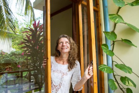 Téléchargez les photos : Femme ouvrant porte sur jardin tropical - en image libre de droit