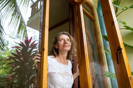 Foto de Mujer abriendo la puerta al jardín tropical - Imagen libre de derechos