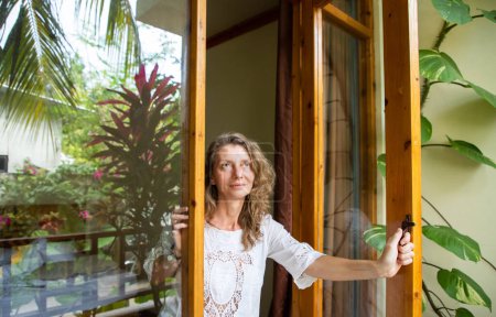 Foto de Mujer abriendo la puerta al jardín tropical - Imagen libre de derechos