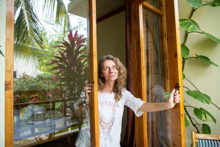 Téléchargez les photos : Femme ouvrant porte sur jardin tropical - en image libre de droit