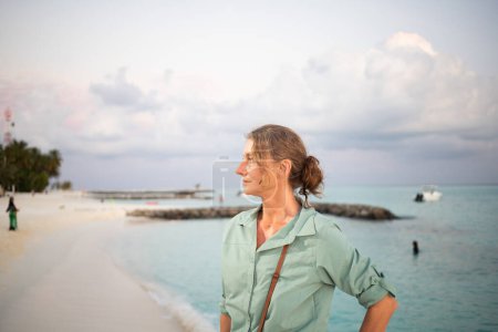 Téléchargez les photos : Femme regardant le coucher de soleil rose sur la liberté de la mer tropicale - en image libre de droit
