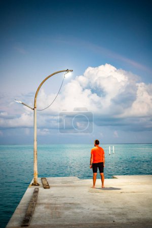 Téléchargez les photos : Homme regardant coucher de soleil nuage sur la liberté de la mer tropicale - en image libre de droit