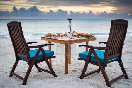 Téléchargez les photos : Romantique table de dîner mise sur la plage coucher de soleil - en image libre de droit