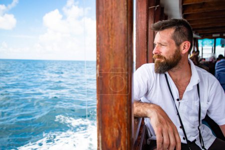 Téléchargez les photos : Bel homme caucasien voyageant sur un ferry local - en image libre de droit