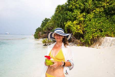 Foto de Mujer sosteniendo coco en la playa tropical - Imagen libre de derechos