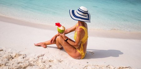 Téléchargez les photos : Femme avec chapeau de paille bronzer sur la plage tropicale - en image libre de droit