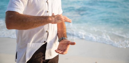 Téléchargez les photos : Homme pratiquant le qigong au bord de la mer - en image libre de droit