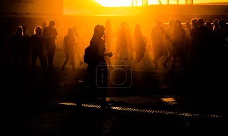Téléchargez les photos : Silhouettes de personnes marchant au coucher du soleil festival - en image libre de droit