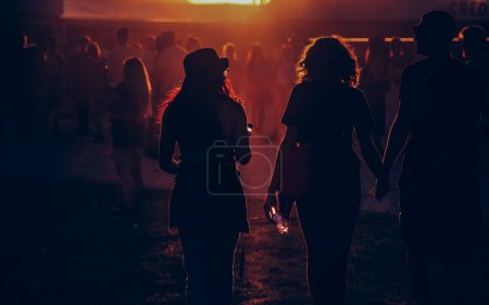 Téléchargez les photos : Silhouettes de personnes marchant au coucher du soleil festival - en image libre de droit