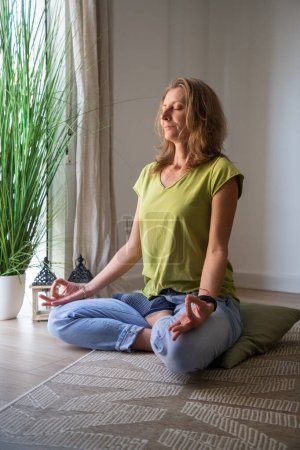 Foto de Mujer meditando en casa en sala de estar - Imagen libre de derechos