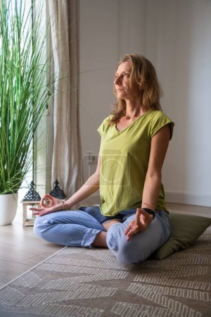 Foto de Mujer meditando en casa en sala de estar - Imagen libre de derechos