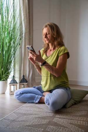 Téléchargez les photos : Femme avec téléphone relaxant dans le salon - en image libre de droit
