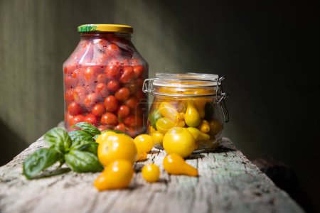 Foto de Tomates cherry rojos y amarillos en un frasco para el invierno - Imagen libre de derechos
