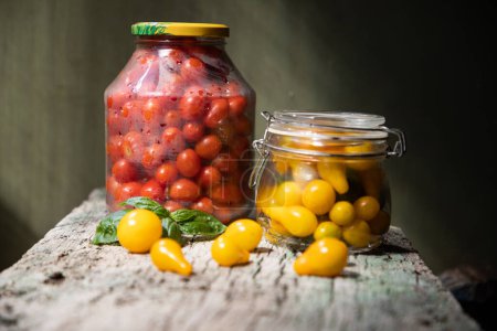 Photo for Red and yellow cherry tomatoes in a jar for winter - Royalty Free Image