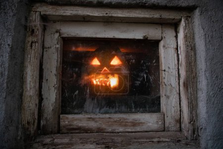 Foto de Calabaza de Halloween asustadiza que brilla en la ventana por la noche - Imagen libre de derechos
