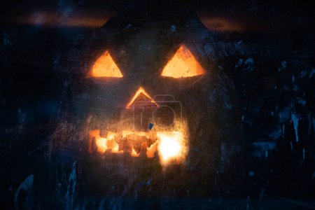 Photo for Scary Halloween pumpkin glowing in window at night - Royalty Free Image