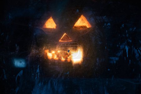 Téléchargez les photos : Effrayant Halloween citrouille luisant dans la fenêtre la nuit - en image libre de droit