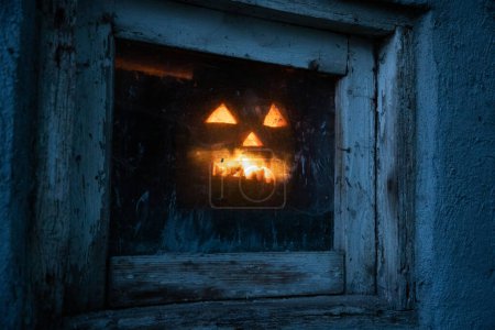 Photo for Scary Halloween pumpkin glowing in window at night - Royalty Free Image