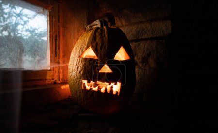 Foto de Calabaza de Halloween asustadiza que brilla en la ventana por la noche - Imagen libre de derechos
