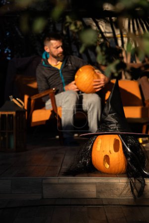 Foto de Hombre tallando calabaza de Halloween en la terraza soleada - Imagen libre de derechos