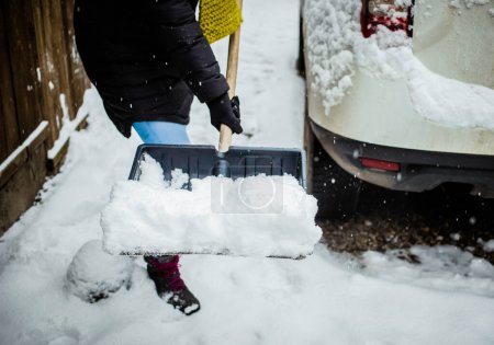Téléchargez les photos : Femme avec pelle nettoyage neige. Pelle d'hiver. Enlever la neige après le blizzard - en image libre de droit