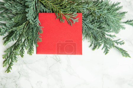 Foto de Tarjeta roja de Navidad en ramas de abeto verde - Imagen libre de derechos