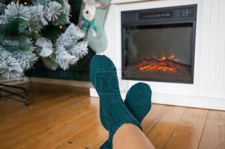Foto de Mujer en calcetines de lana calentándose delante de firepalce - Imagen libre de derechos