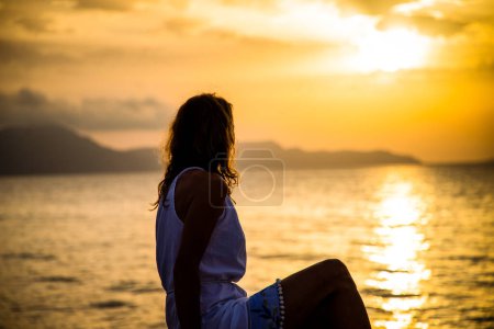 Téléchargez les photos : Femme profiter du lever du soleil au bord de la mer - en image libre de droit