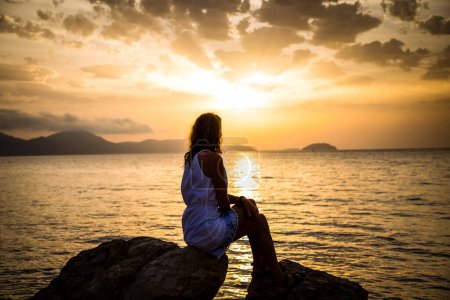 Téléchargez les photos : Femme profiter du lever du soleil au bord de la mer - en image libre de droit