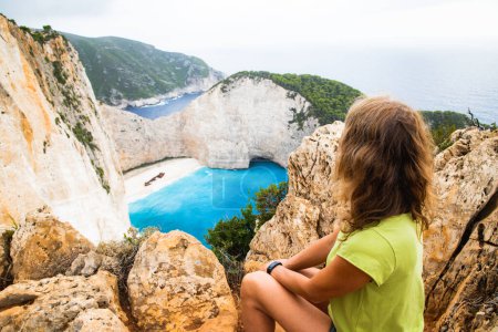 Téléchargez les photos : Femme regardant Navagio plage avec le célèbre navire naufragé à Zante Grèce - en image libre de droit