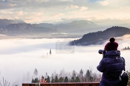 Téléchargez les photos : Photographe femme prenant des photos de lever de soleil incroyable au lac Bled du point de vue d'Ojstrica, Slovénie, Europe - arrière-plan de voyage - en image libre de droit