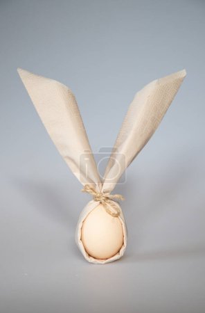 Photo for Egg wrapped in easter bunny shaped napkin - Royalty Free Image